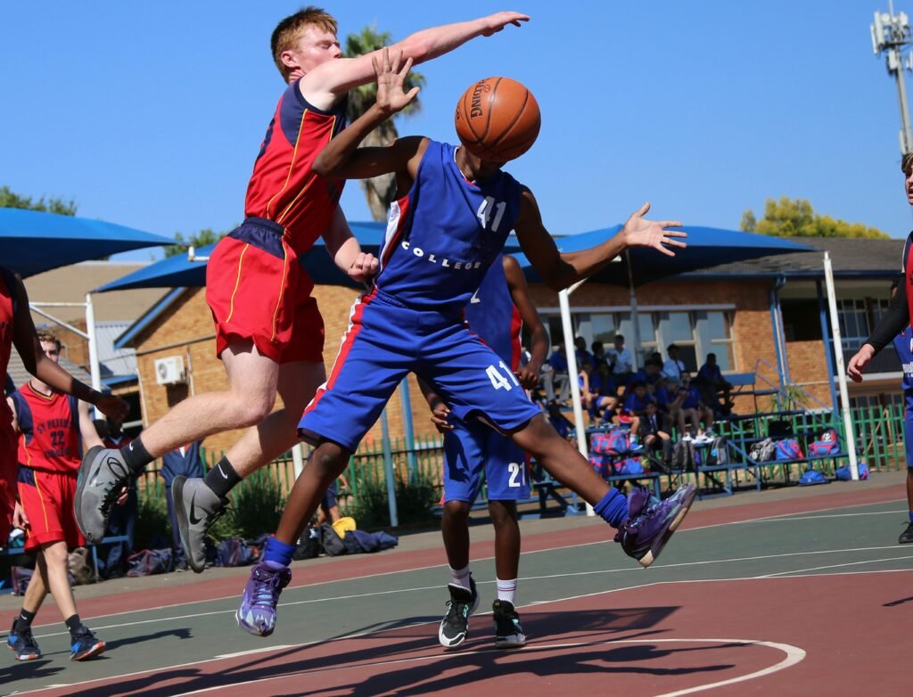Two athletes playing a competitive basketball game on an outdoor court.